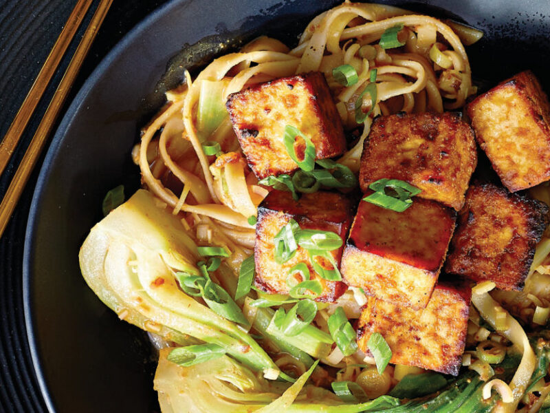 Thai Noodle Bowls with Crispy Air-Fried Tofu in a black ceramic bowl with bamboo chopsticks on the left hand side