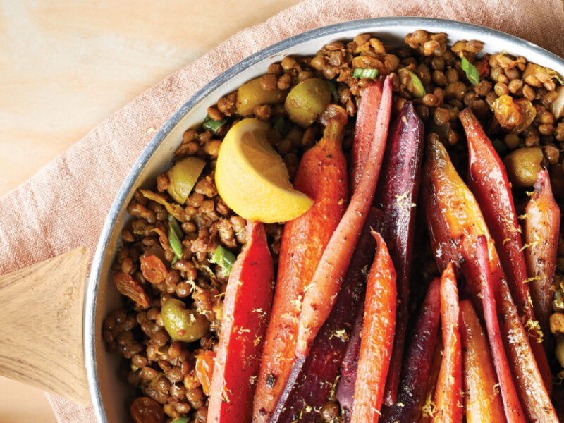 Za'atar Carrots and Lentils in a ceramic dish with a wedge of lemon on a pale apricot cloth napkin