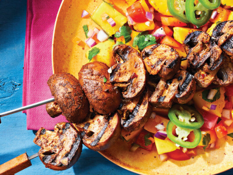 Spicy Jerk Mushroom Kabobs with Mango Salsa on a yellow plate on a bright pink napkin on a blue table