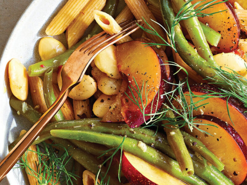 Plum Pasta Salad with Roasted Garlic Vinaigrette in a white bowl with a copper-colored fork