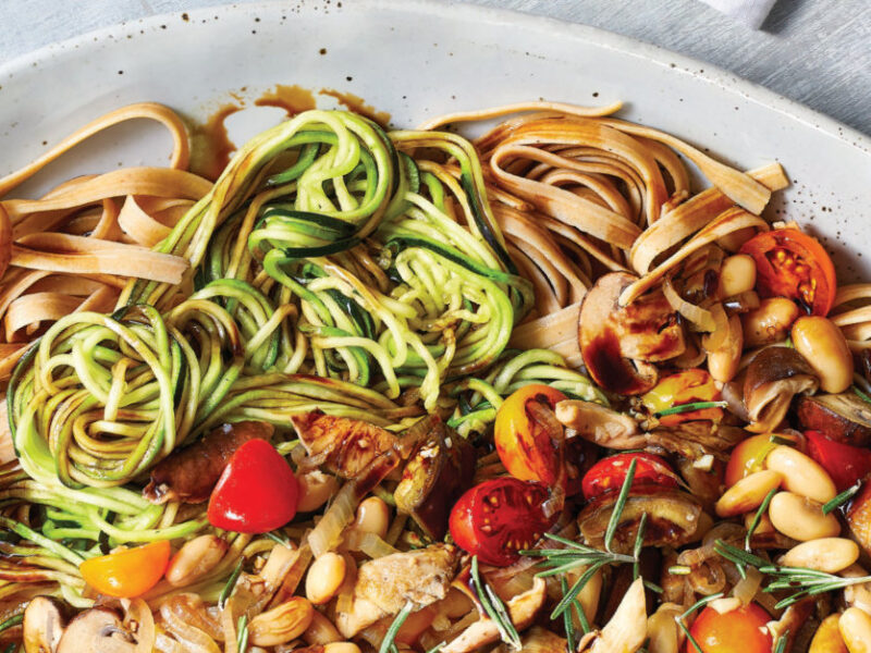 Whole Grain Fettuccine with Zoodles and Balsamic-Glazed Vegetables in a white ceramic bowl against a pale grey background