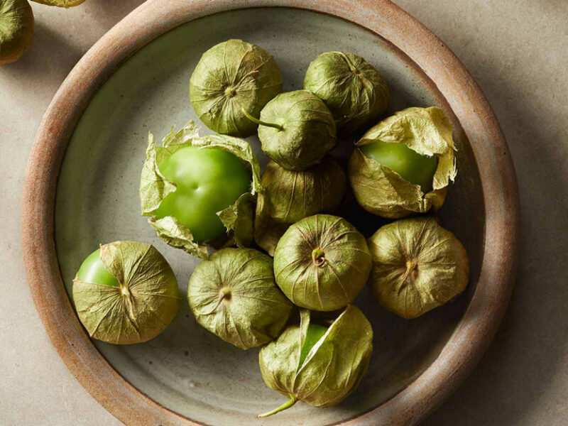 whole tomatillos in their husks in a ceramic bowl in natural lighting