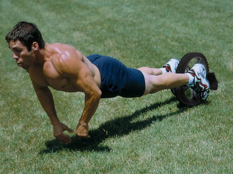 bare chested man using power wheel outside on the grass