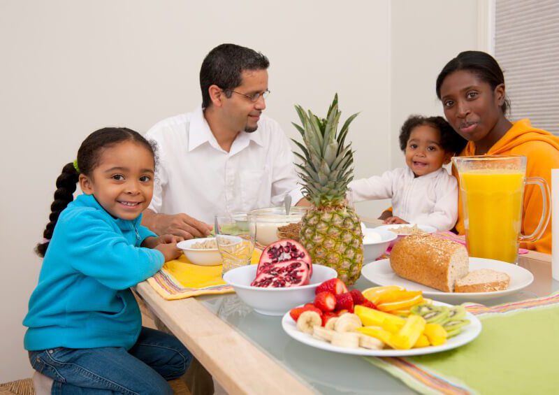 A mixed African American and Hispanic family at the dinner table eating