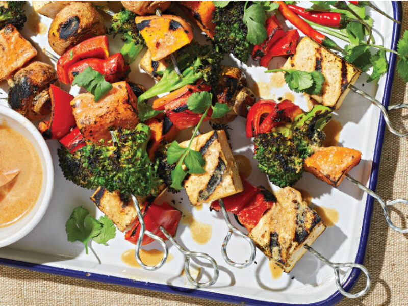 Grilled Veggie and Tofu Skewers on a white platter with a small bowl of Peanut Sauce to the side