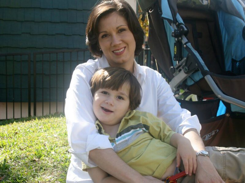 Shelly Vincent sits on the lawn with her young boy on her lap