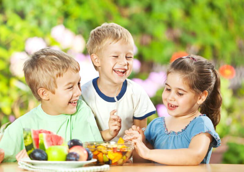 Three young children eating fruit salad