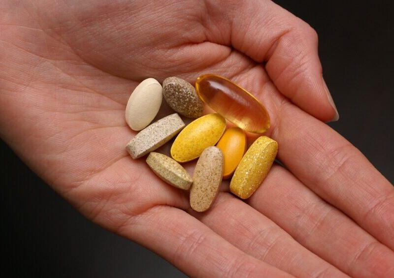 Outstretched palm holding large colorful supplements