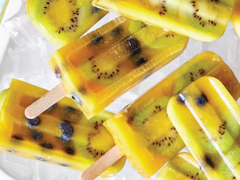 Half a dozen Kiwi-Blueberry Orange Ice Pops on a white platter
