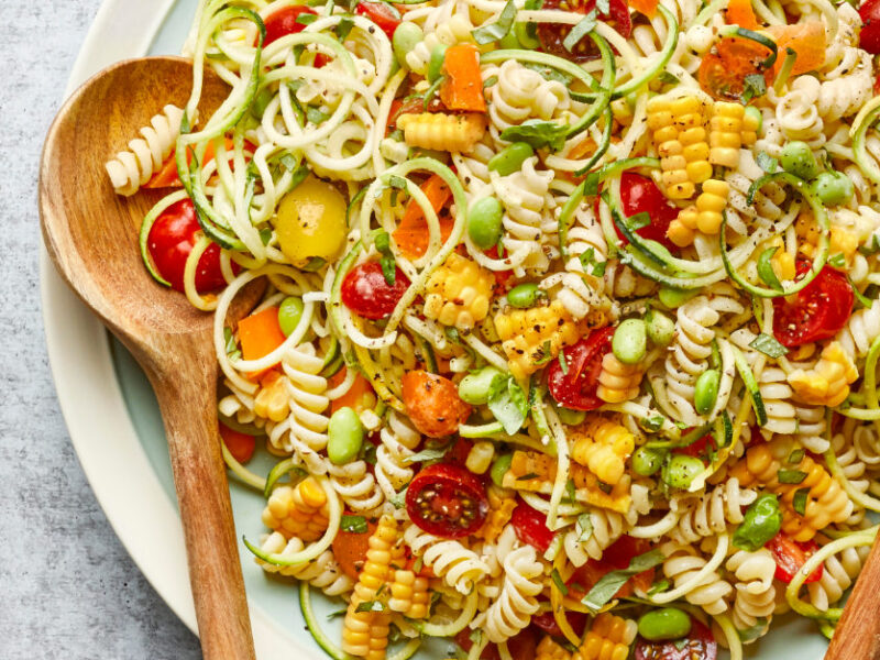 Confetti Corn and Pasta Bowl on a white platter with wooden serving spoons