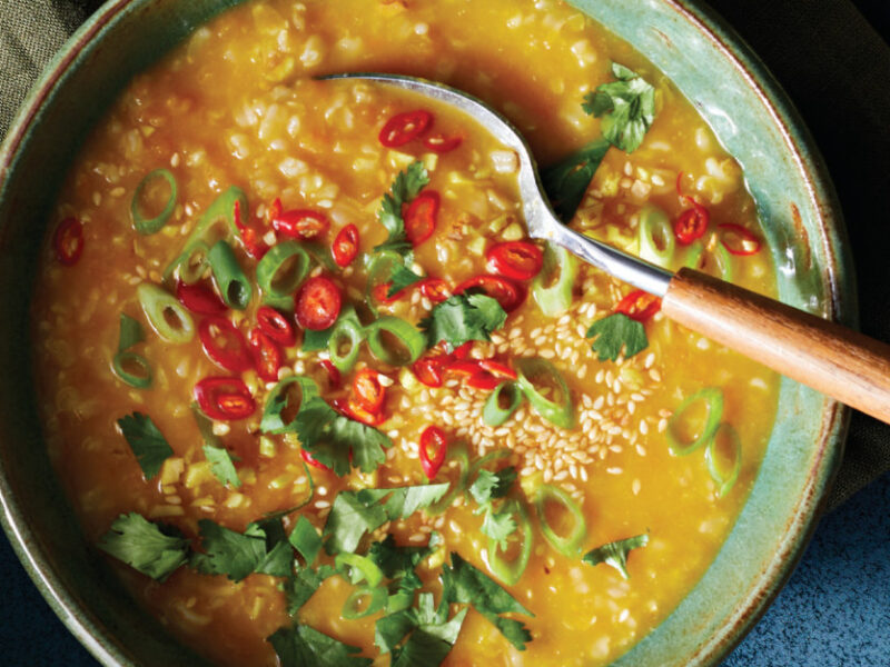Silky Squash Vietnamese Rice Porridge in a green ceramic bowl with a wooden-handled spoon resting in the bowl