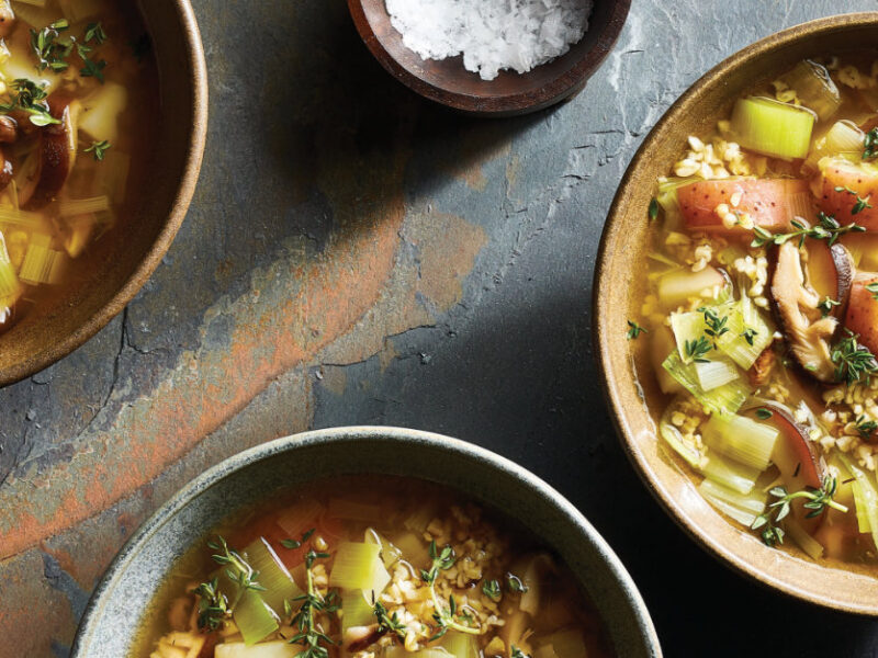 3 Bowls of 8-Ingredient Leek and Mushroom Soup sitting on a granite counter next to a small bowl of coarsely ground sea salt