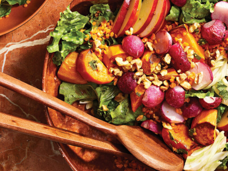 Roasted Radish Salad with Sweet Potato and Apple in a wooden serving bowl with wooden serving spoons resting in the bowl