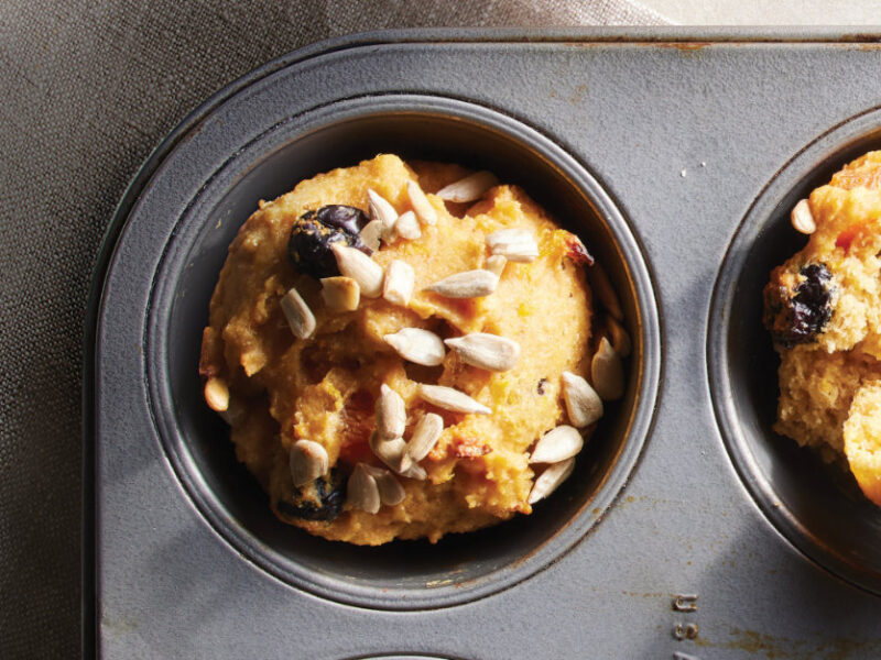 Two Vegan Cranberry Orange Muffins in a metal muffin pan
