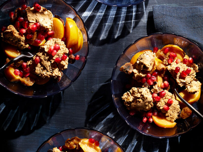 Two servings of Persimmon Fig Crisp with Golden Figs in glass bowls with pomegranate arils sprinkled on top