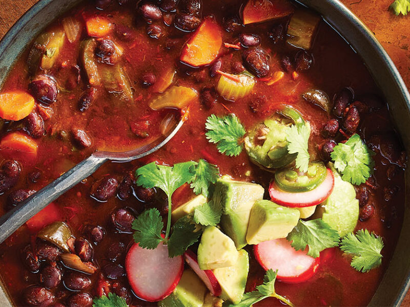 A bowl of Black Bean Chili garnished with quick-pickled avocado, radish, and jalapeño