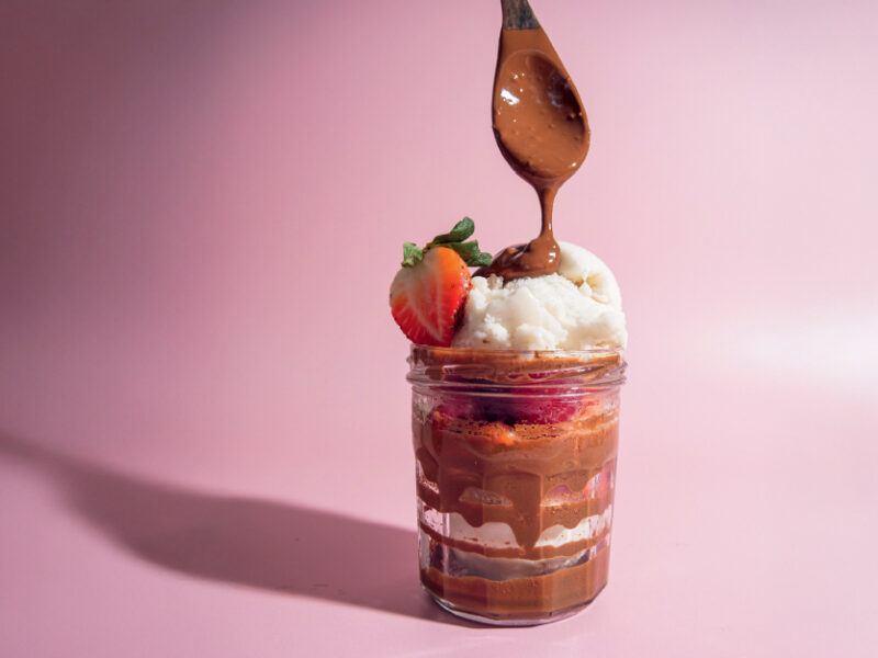 Chef Bai's Oat Chocolate Put-on-Everything Sauce drizzled over a tall glass of ice cream and strawberries