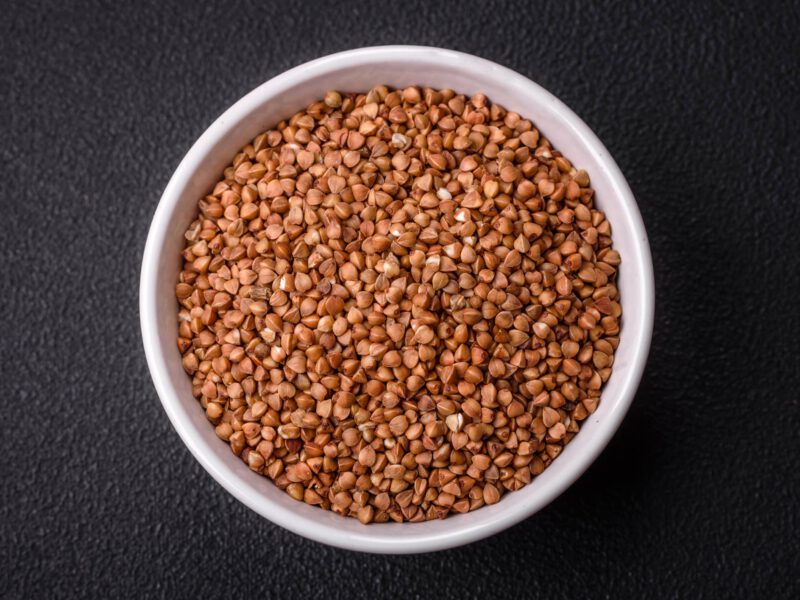 Buckwheat graots in a bowl on a solid gray background