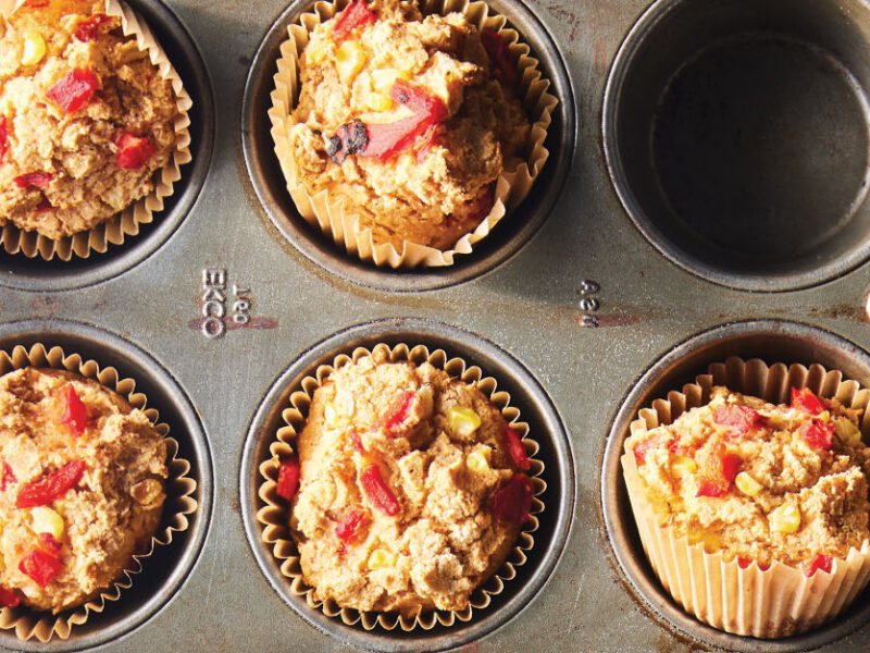 A muffin try zoomed in on 5 Cornmeal Muffins specked with red and yellow