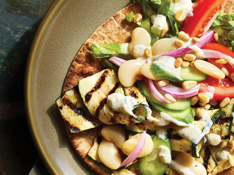 Vegan Gyros with Zucchini on an earthy green ceramic plate drizzled with Tzatziki Sauce