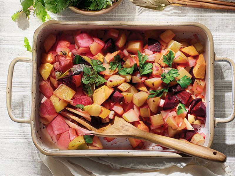 An oven tray of Vegan Red Flannel Hash on a pale grey kitchen town with a wooden serving spoon resting in the dish