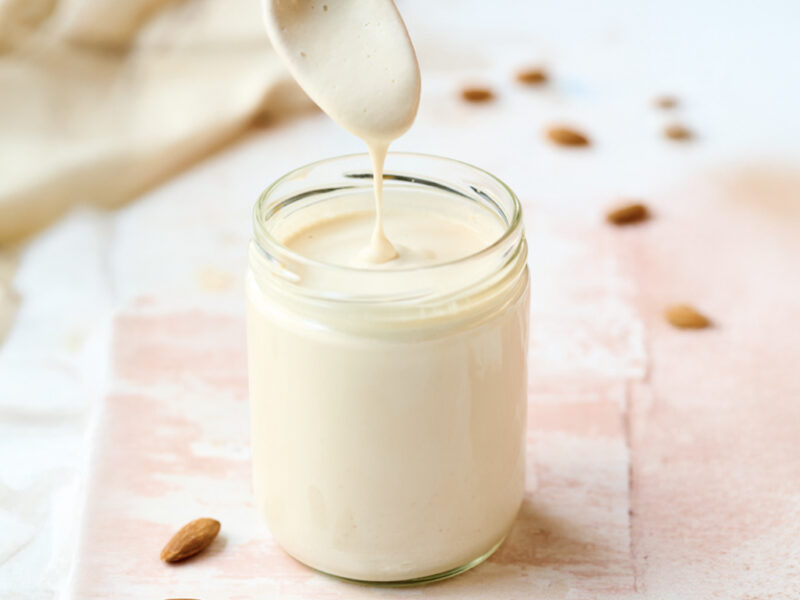 Almond Crema (Crema de Almendras) in a glass with a white jug above, pouring in crema
