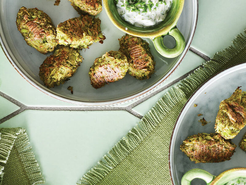 Two plates with Potato and Broccoli Tots , each plate has a small bowl of creamy white dipping sauce