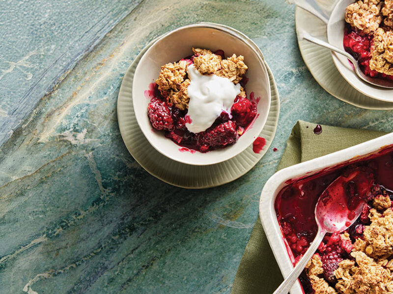 Not-Picky Fruit Crisp in a white casserole dish with one serving in a white bowl, topped with Aquafaba Whipped Cream