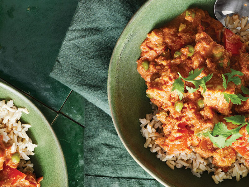 Two green ceramic bowls of brown rice topped with Carleigh Brodug’s Any Vegetable Curry and a garnish of fresh cilantro