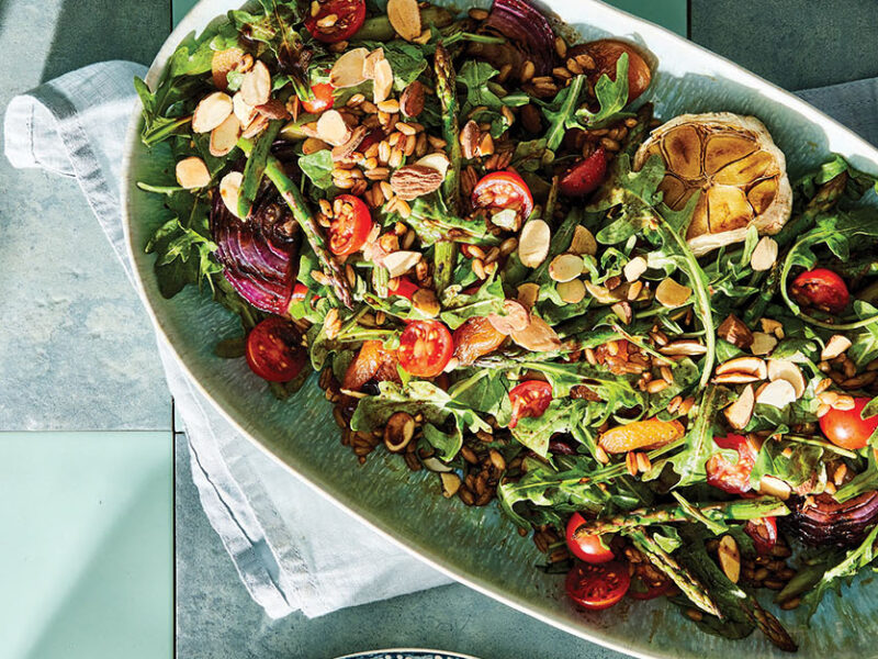 A large white platter of Grilled Asparagus Salad with Dried Apricots and Almonds on a table set with pale blue tablecloth and napkins