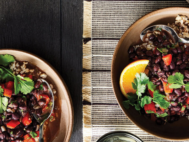 Two bowls of Vegan Feijoada (Brazilian Black Bean Stew) topped with fresh cilantro and a wedge of orange