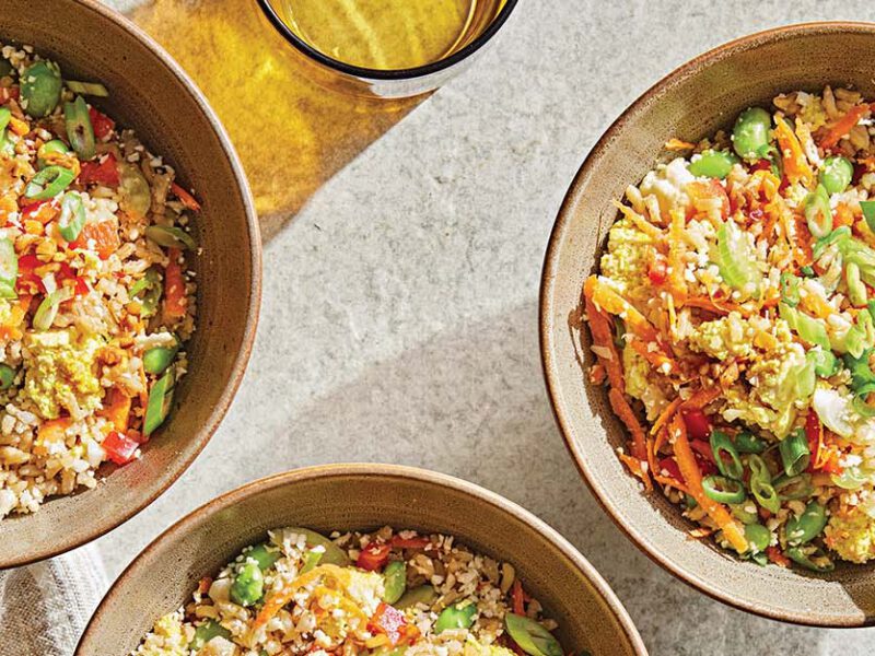 Three brown ceramic serving bowls of Miso Tofu Rice Bowl with Crunchy Veggies next to amber-hued water glasses