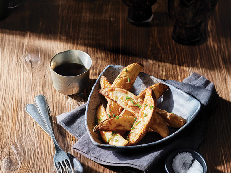A bowl of Air-Fryer Pub Fries next to a small dipping bowl of malt vinegar