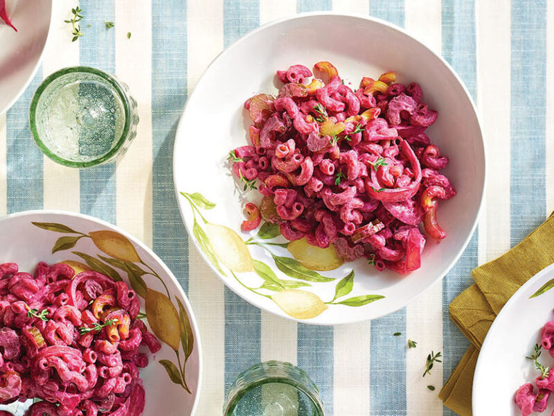 Four white bowls of Easy, Creamy Beet Pasta on a pale blue and white striped table cloth