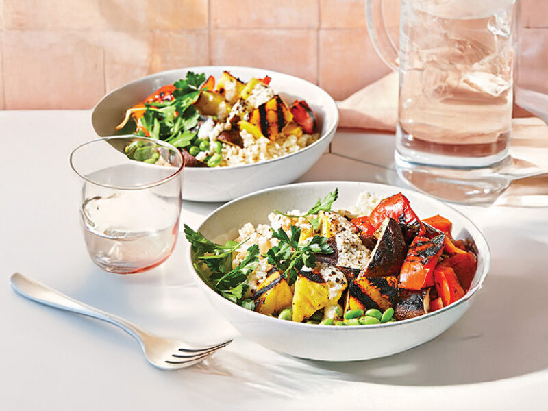 Grilled Pineapple Veggie Bowl in two bowls on a white table setting with a peach background