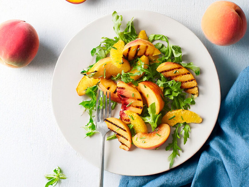 Peachy-Orange Arugula Salad on a white plate