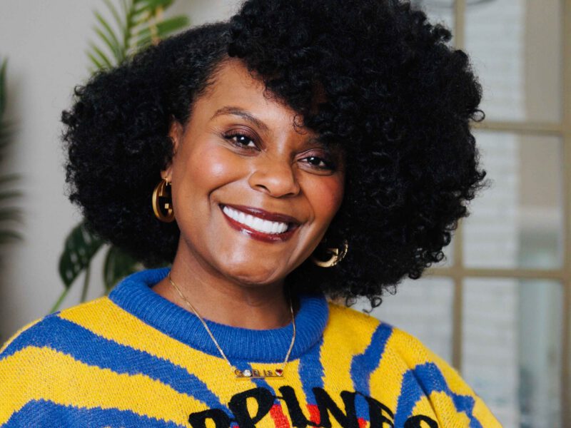 Headshot of actress and vegan influencer Tabitha Brown wearing a colorful yellow and blue striped sweater