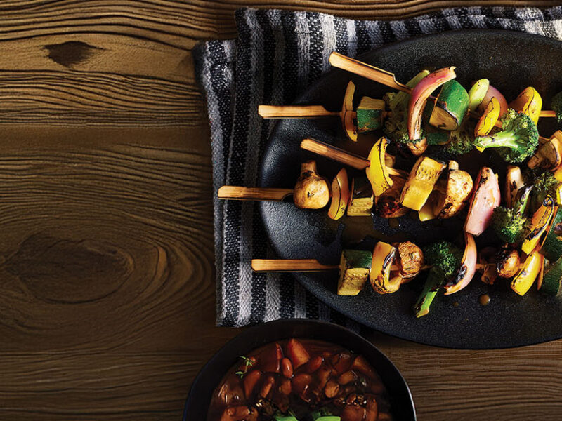 Vegetable Kabobs with BBQ Beans on a platter next to a small bowl of BBQ beans