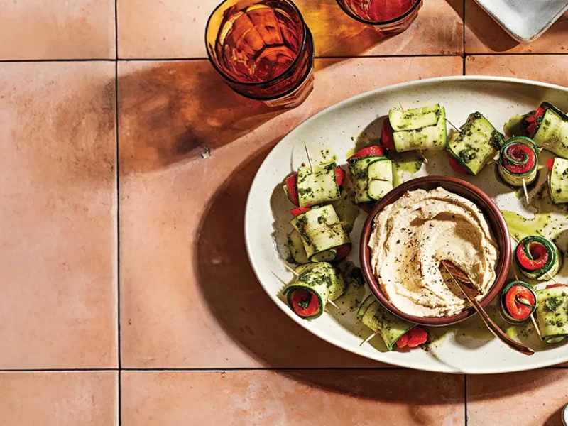 Roasted Red Pepper and Zucchini Roll-Ups on a white plate on a terracotta tile
