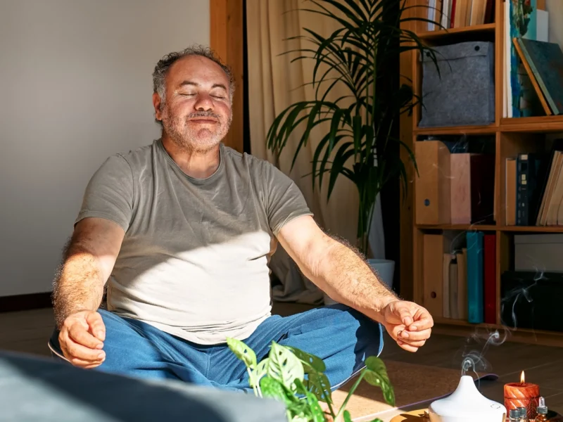 Man meditating in his living room, smiling slightly