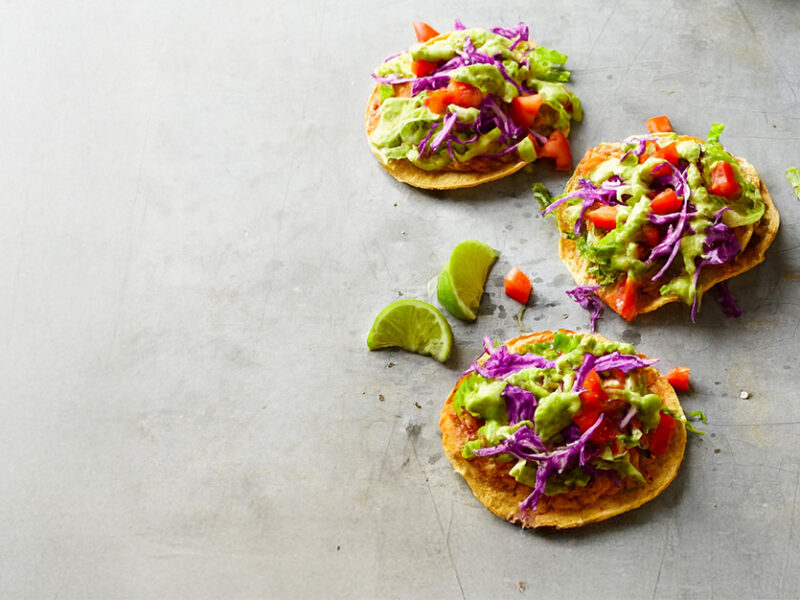 Three Southwest Chipotle Tostadas on a grey counter top with wedges of lime