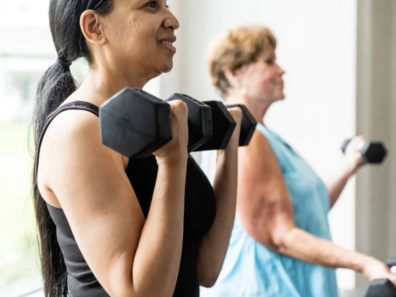 A middle-aged woman and senior woman lifting weights in a gym