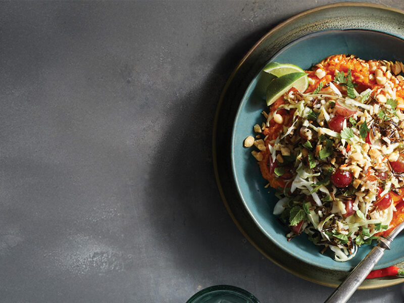 A bowl of Spicy Thai Cabbage and Rice Salad on a dark grey background