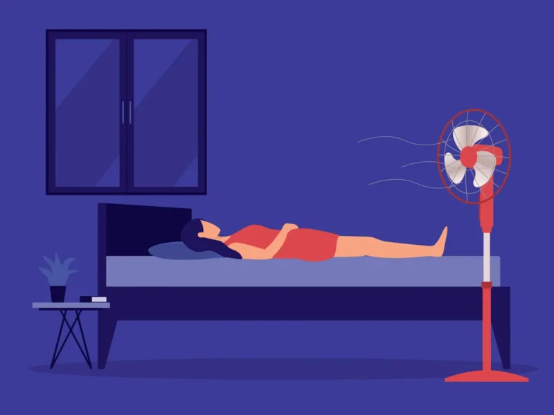 Illustration of woman lying in bed on top of covers with the fan on to combat hot flashes. Deep purple background, lighter figure in an orange dress.