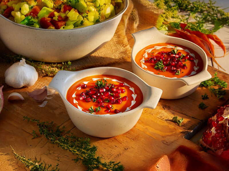 Two bowls of Creamy Carrot Soup as part of a vegan Thanksgiving spread