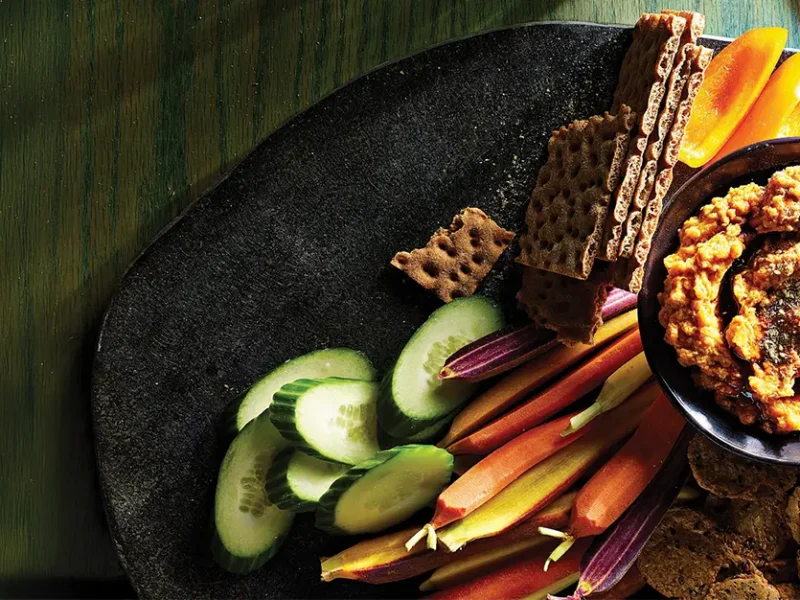 Sweet Potato Tahini Dip with Za'atar on a platter with cucumber, colorful heirloom carrots, and whole grain crackers