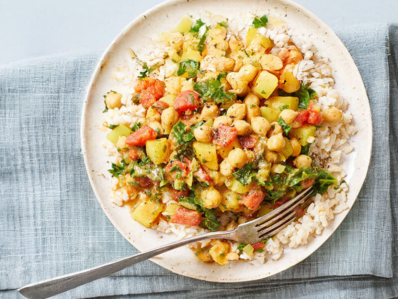Chickpea Curry Stew with Kale on a white plate in a pale blue folded napkin