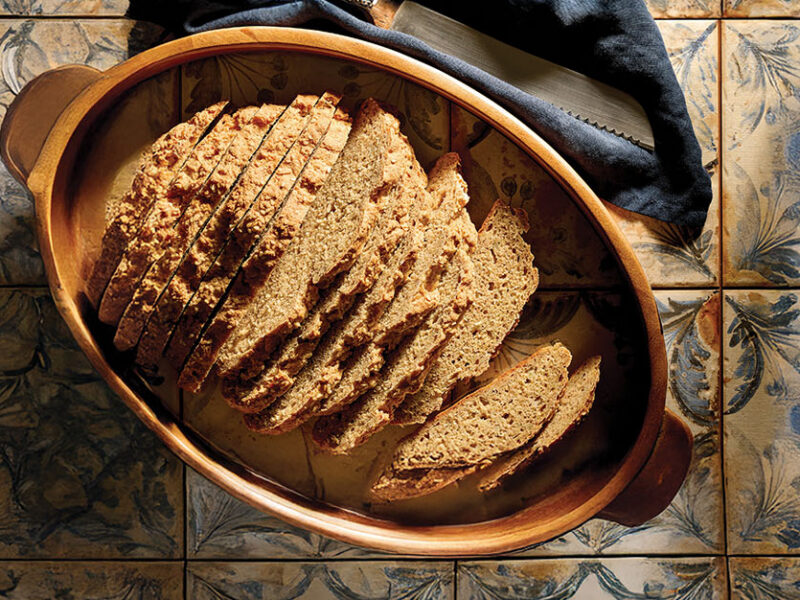 No-Knead Boule Bread in an oval dish on a rustic tiled background