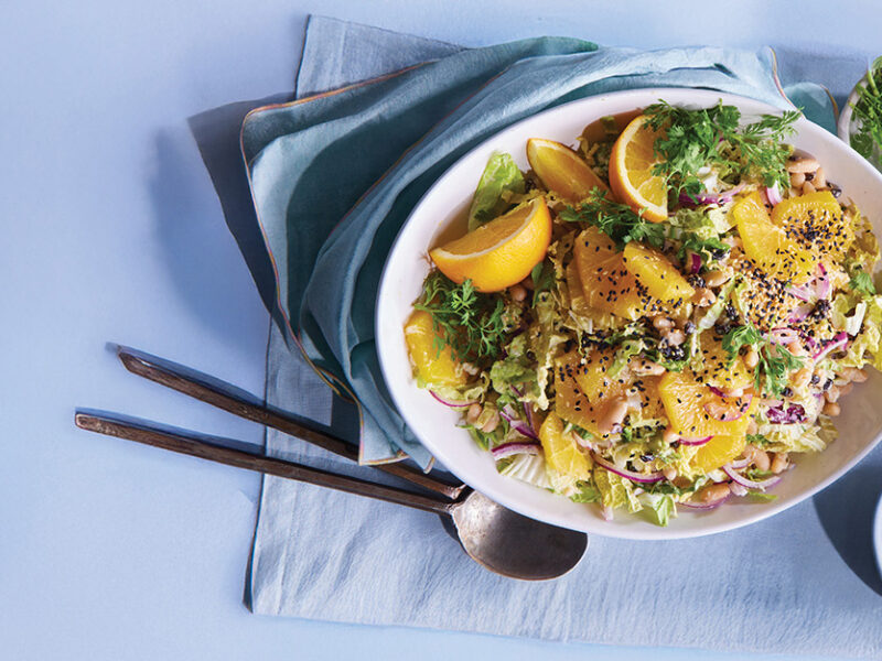 White Bean and Shaved Cabbage Salad with Orange Dressing in white plate on a blue tablecloth