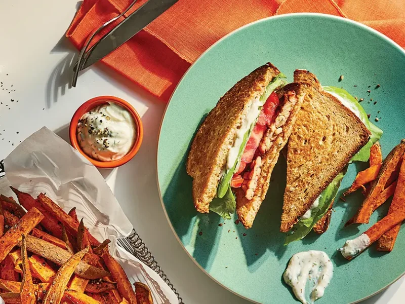 Tempeh BLT with Vegan Mayo on a plate with fries in a bowl on the side